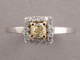 a close up of a ring with a yellow diamond surrounded by white diamonds