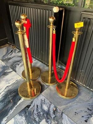 two golden stanches with red ropes on the floor