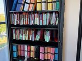 une bibliothèque noire remplie de livres et une chaise devant une fenêtre