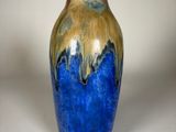 un vase bleu et or posé sur une surface blanche