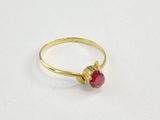 gros plan d'une bague en or avec une pierre rouge