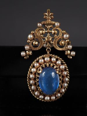 un gros plan d'une broche ornée de perles et d'une pierre bleue