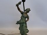 une statue représentant une femme tenant une lampe posée sur une table