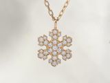 a close up of a snowflake pendant on a gold chain
