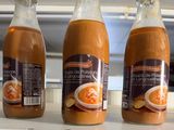 three bottles of soup sit on a shelf in a kitchen