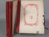 an old book with a red cover sitting on top of a metal stand