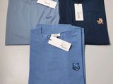 trois t-shirts posés sur une table, avec une étiquette de prix