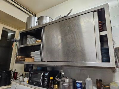une armoire en acier inoxydable dans la cuisine, sur laquelle sont posées des casseroles et des poêles