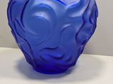 un vase en verre bleu posé sur une table blanche