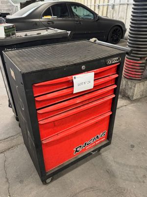 une boîte à outils noire et rouge posée sur le trottoir