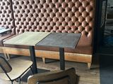 two tables and two chairs in front of a brick wall