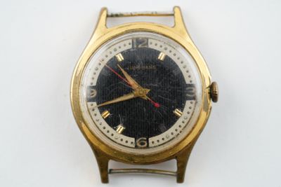 une montre-bracelet en or avec un cadran noir sur une surface blanche