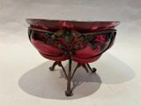 a red glass bowl on a stand on a white surface