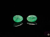 a pair of emerald earrings on a black surface