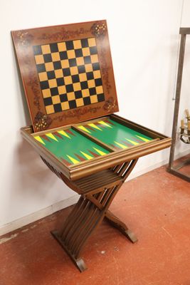 Table à jeu et paire de fauteuils curule en bois naturel.