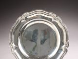 a silver plate on a stand on a white surface