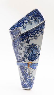 un vase bleu et blanc orné d'une anse dorée sur fond blanc