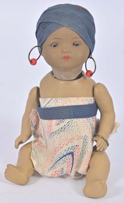 a small doll with a turban sitting on a white surface