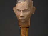 a wooden sculpture of a man ' s head on a stand