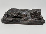 statue en bronze représentant un chien couché sur un socle en bois