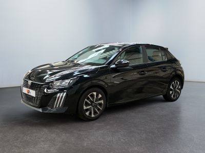 Une voiture noire est garée dans une pièce aux murs blancs.