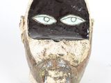a black and white mask with green eyes on a white background