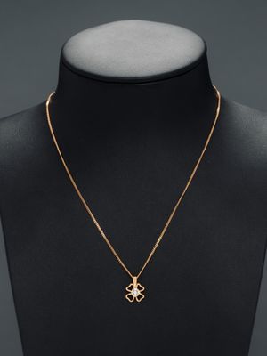 a gold necklace with a cross pendant on a mannequin neck