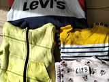 une boîte en carton sur laquelle sont posés des vêtements et un oreiller