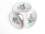 three plates with flowers painted on them on a white surface