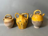 trois vases jaunes posés les uns à côté des autres sur une surface grise