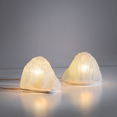 une paire de lampes en verre blanc posées sur une surface blanche, avec un fond blanc