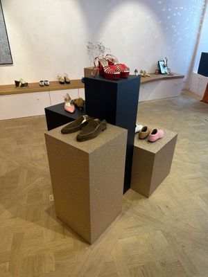 Plusieurs paires de chaussures sont exposées dans une pièce au sol en parquet.