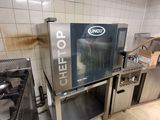 un homme debout dans une cuisine, à côté d'un four