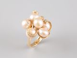 a gold ring with pearls and diamonds on a white background