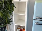 une grande étagère blanche sur laquelle se trouvent une bouteille de vin et une plante en pot