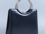 sac à main en cuir noir avec une poignée en métal sur fond blanc