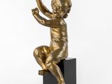 une statue en bronze représentant un enfant assis sur un bloc