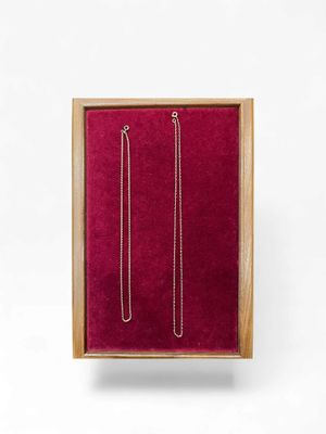 a pair of earrings in a wooden box on a white background