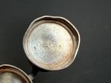 two silver pots sitting next to each other on a table