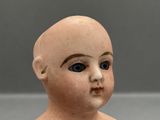 a small doll with a bald head and blue eyes