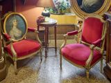 deux chaises rouges dans un coin d'une pièce où est accroché un tableau au mur
