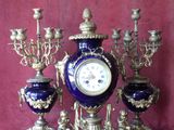 a blue and gold clock on a stand with candles