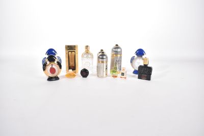 cinq flacons de parfum miniatures posés sur une surface blanche