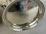 a silver plate with a handle on a table next to an apple