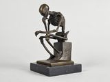 statue of a skeleton sitting on top of a box with a skull on it