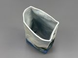 a small blue and white vase on a gray surface