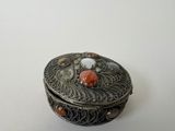 a small silver box with a red and white decoration on it