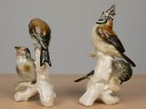 two figurines of birds sitting on top of a wooden table