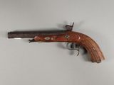 un petit pistolet en bois accroché au mur, à côté d'un mur blanc