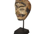 a close up of a wooden mask on a stand on a white background